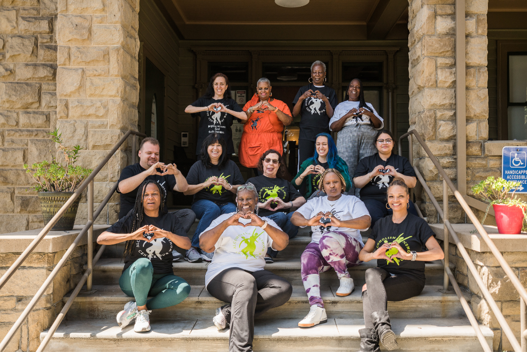 A group of ACW Staff Members sitting on the front steps of the ACW Residence Building