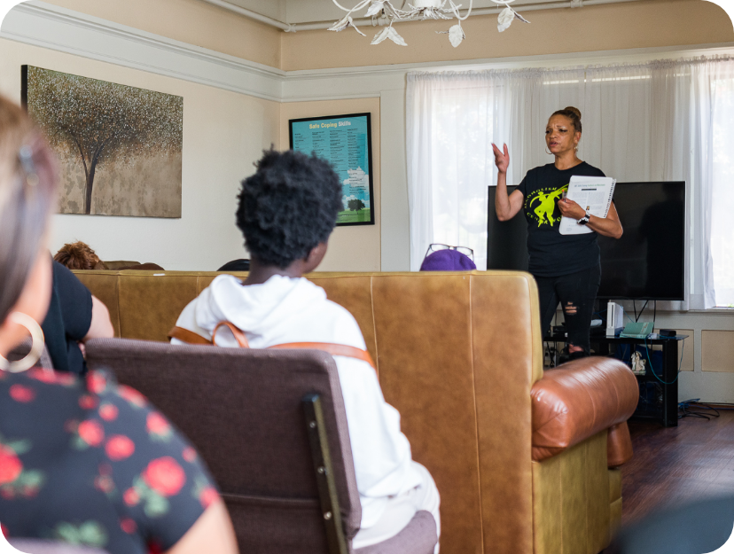 A group of residences at a group therapy session listening to an ACW staff member